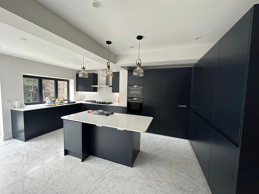 Wide open-plan kitchen with dark units and integrated appliances